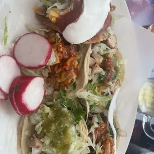 Assortment of tacos(potato (sour cream) shrimp (red salsa) carnitas (green salsa) , asada (red salsa) and chicken (streak of salsa)