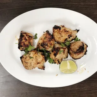 a plate of chicken with a lime wedge