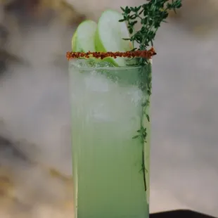 a green cocktail with apple garnish