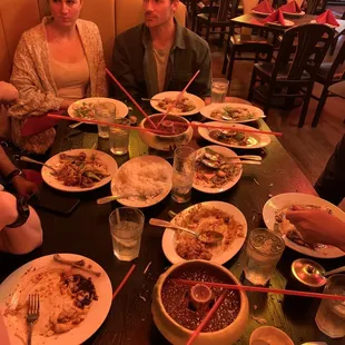 a group of people sitting at a table with plates of food