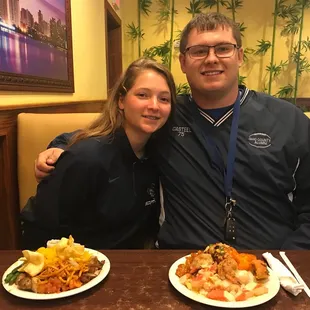 a man and a woman sitting at a table with plates of food