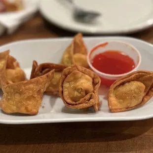 a plate of wontons with dipping sauce