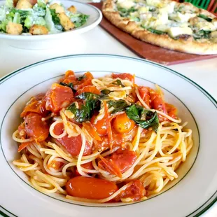 a plate of pasta with tomatoes and spinach