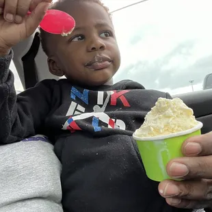a child holding a cup of ice cream