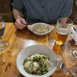 a man sitting at a table with a bowl of food and a glass of beer