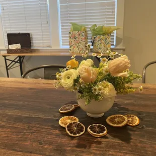 an arrangement of flowers and fruit on a table