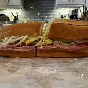 Cold cut sub: lettuce, tomato, mayonnaise, onion, oil-vinegar, served on a soft roll.