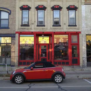 a red car parked in front of a restaurant