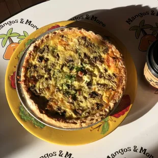 a quiche on a plate with a cup of coffee