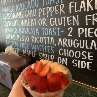 a hand holding a bowl of fruit