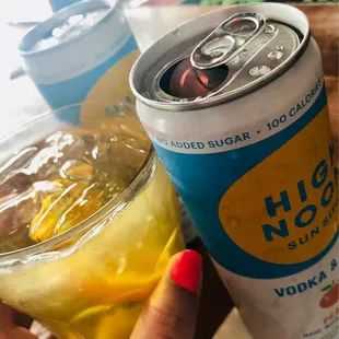 a person holding a can of high noon