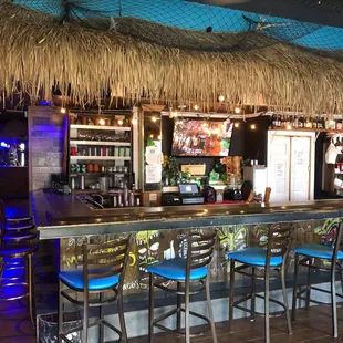 a tiki bar with blue stools