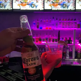 a person holding a bottle of corona beer