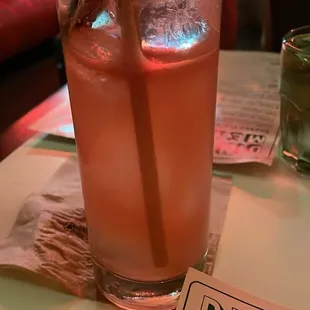 a glass of pink drink with a straw on a table