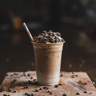 a cold drink with coffee beans and a straw