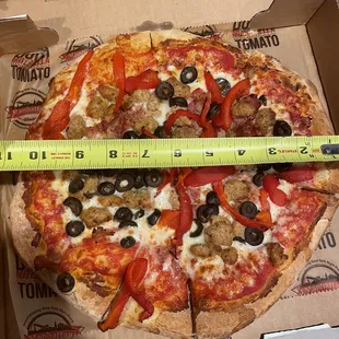 a pizza in a box with a measuring tape