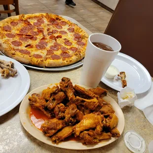 a plate of chicken wings and a pizza on a table