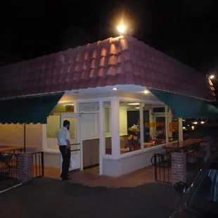 a man standing outside of a restaurant at night