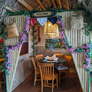 a tiki hut with a table and chairs