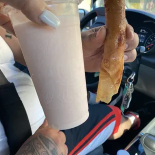 a person holding a donut and a drink