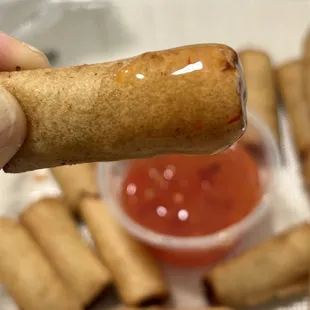 a hand holding a hot dog with ketchup