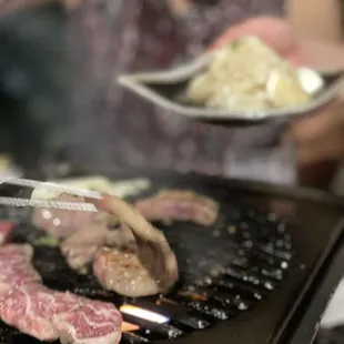 a woman cooking meat on a grill