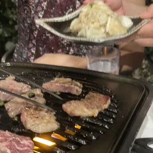 a woman cooking steaks on a grill