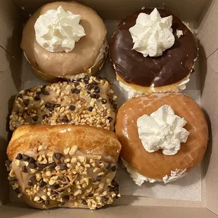 Maple filled with whipped cream, chocolate filled with whipped cream, glaze filled with whipped cream, and Reese&apos;s donuts