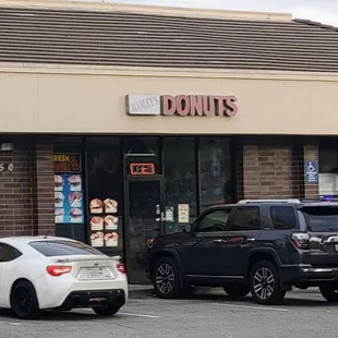 two cars parked in front of a donut shop