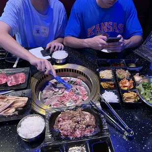 two men sitting at a table with food