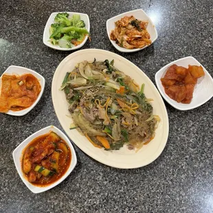 Jabchae (stir-fried noodles with beef and vegetables) surrounded by banchan dishes (comes complimentary)