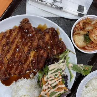 a plate of meat and rice with a side salad