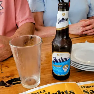 a woman sitting at a table with a beer