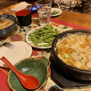 a bowl of soup and bowls of green beans on a table