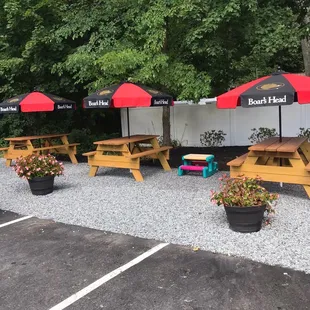 a row of picnic tables with red umbrellas