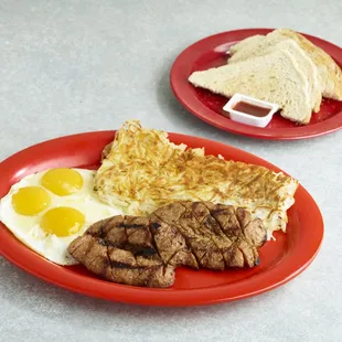 a steak and eggs on a red plate
