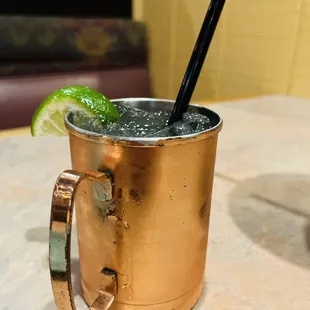 a copper mug with a straw and a lime slice