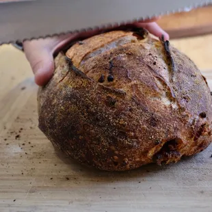 a person cutting a loaf of bread
