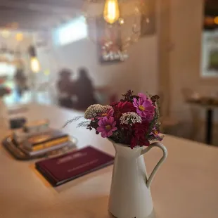 a pitcher of flowers on a table