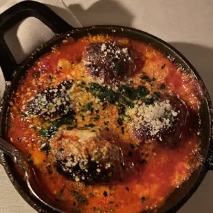 a bowl of soup with meatballs and parmesan cheese