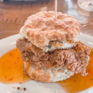 a fried chicken sandwich with a biscuit on a white plate