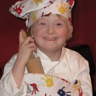 a child in a chef's hat holding a wooden spatula