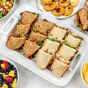a spread of sandwiches and fruit salads