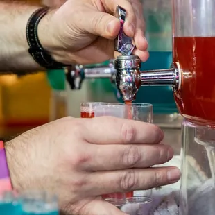 a person filling a drink from a beverage dispenser