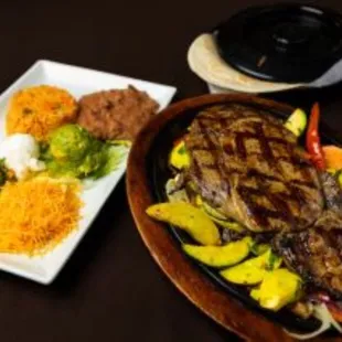 a plate of steak, rice, and vegetables