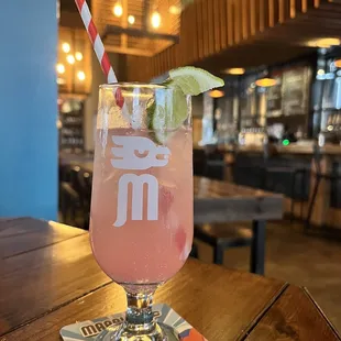 a pink drink with a straw and a lime slice
