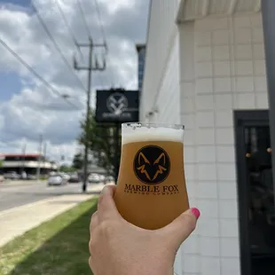 a hand holding a glass of beer