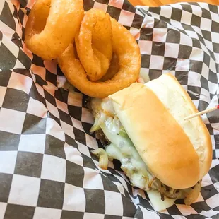 Half of a philly cheese steak sandwich + onion rings