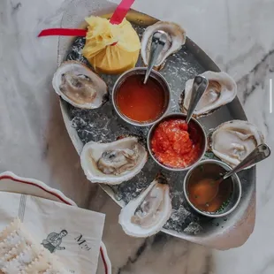 a platter of oysters and dipping sauces