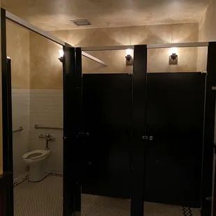 a public restroom with black stalls